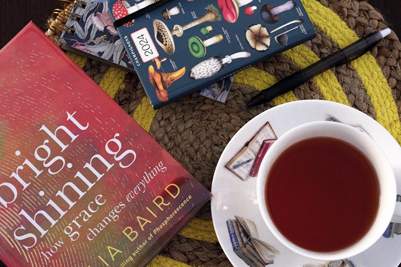 A copy of Julia Baird's 'Bright Shining' with a cuppa and a 2024 planner covered in mushrooms. 