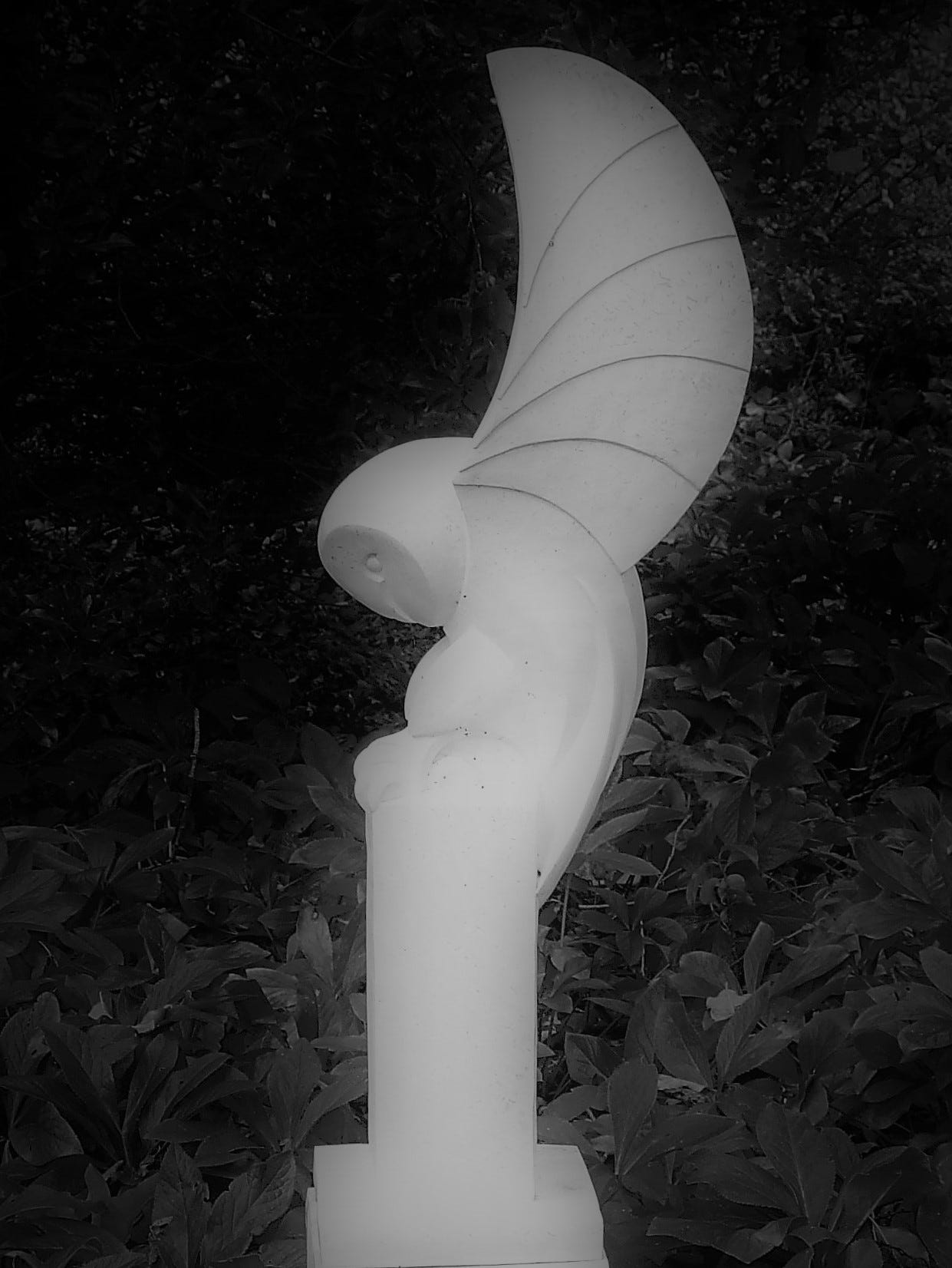 A white marble sculpture of a swooping owl set on a plinth.