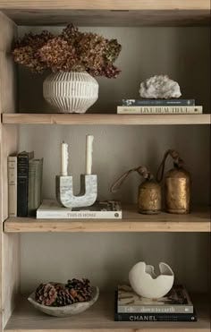 This may contain: shelves with books, candles and vases on them This may contain: shelves with books, candles and vases on them