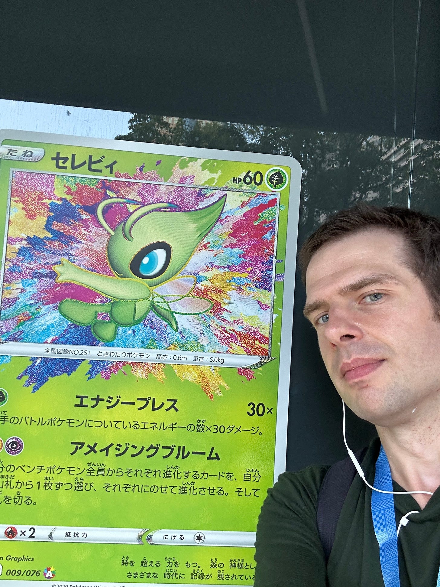 Joe standing with a giant Celebi card from Vivid Voltage during his trip to the 2023 Pokémon World Championships