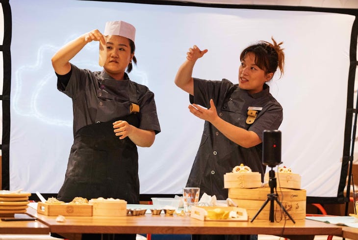 Two women demonstrating how to make dumplings