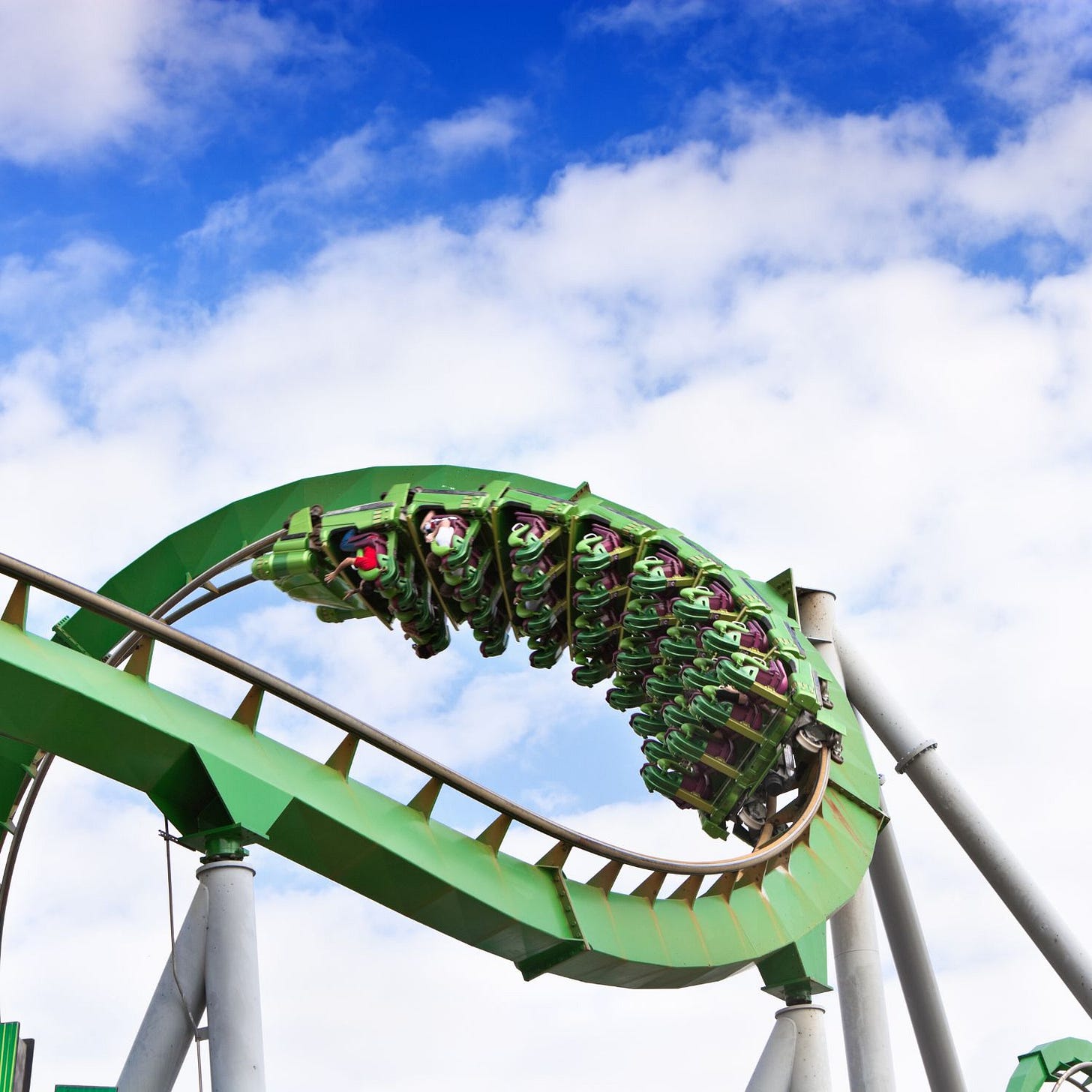 green rollercoaster and clouds in a blue sky