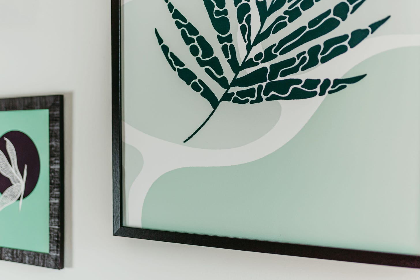 two framed artworks, green illustrations of leaves and a dragonfly in pastel green