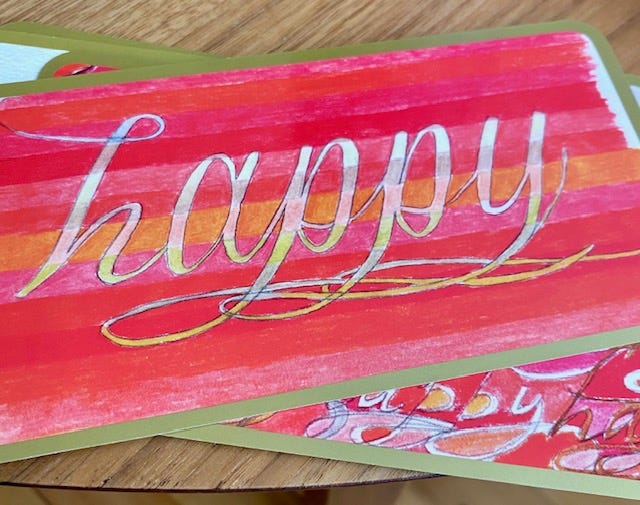 Photo of a card that reads: happy; against a red stripey background.