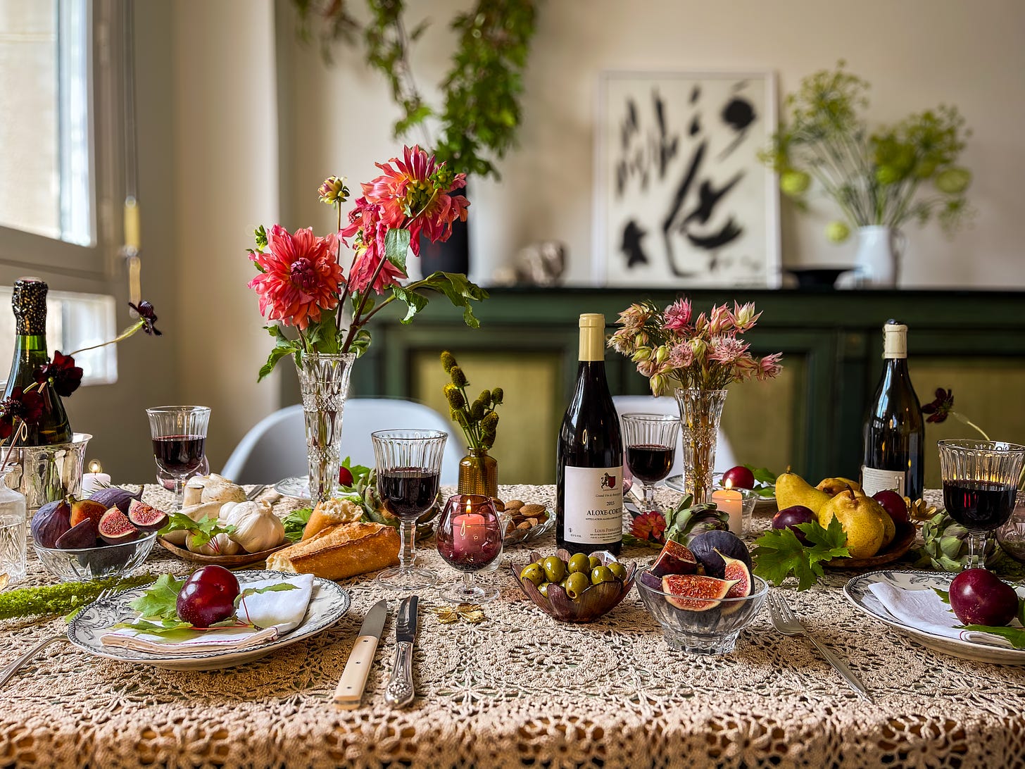 A holiday table setting inspiration with lace tablecloth, fruits, olives, flowers, candles and wine in Paris