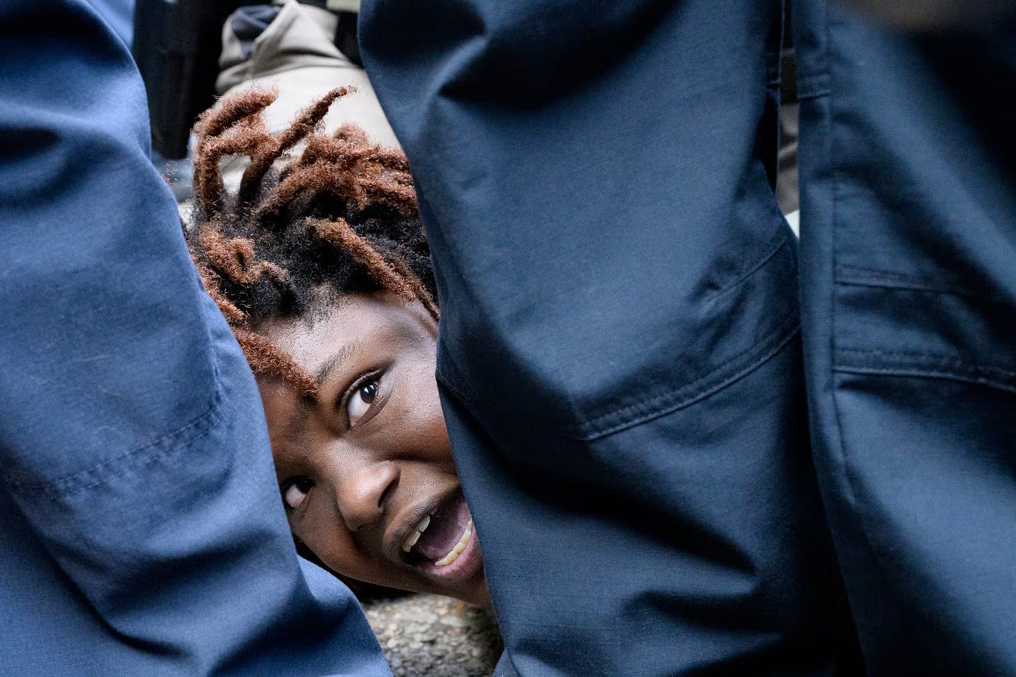 Closeup of terrified young black woman pinned down on the ground by the police.