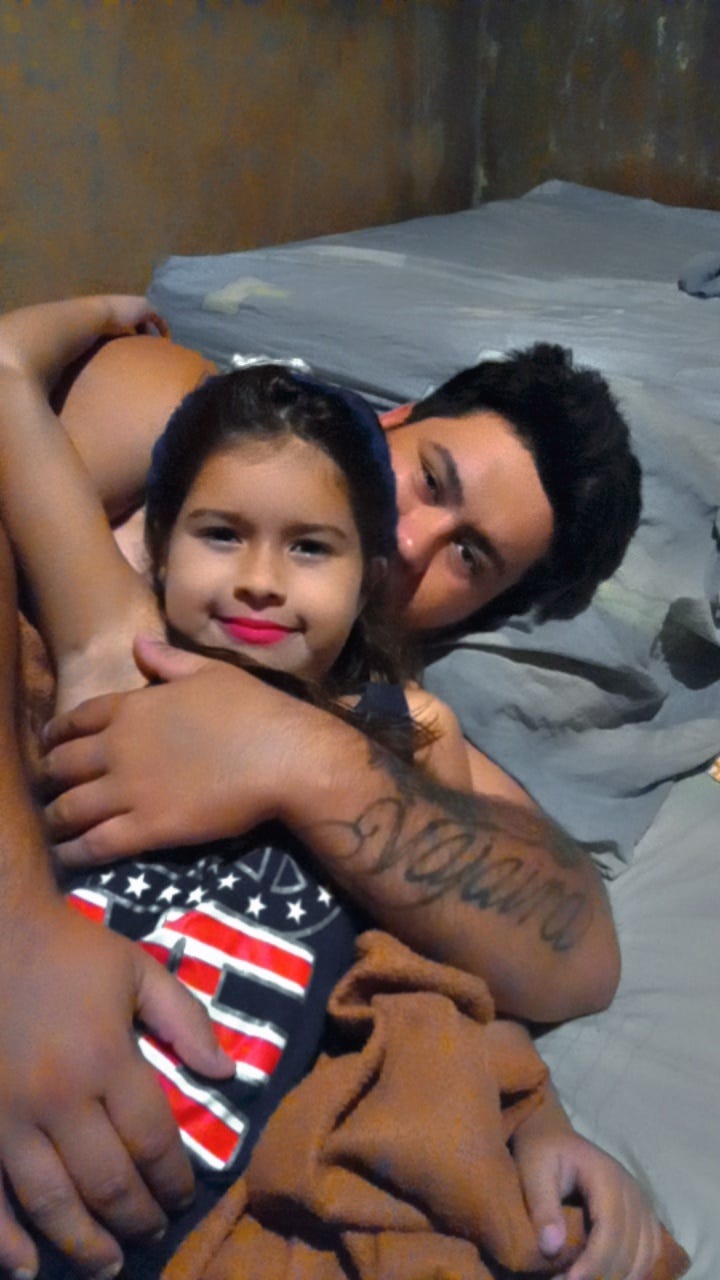 a father holds his daughter close as they pose for a picture a father holds his daughter close as they pose for a picture
