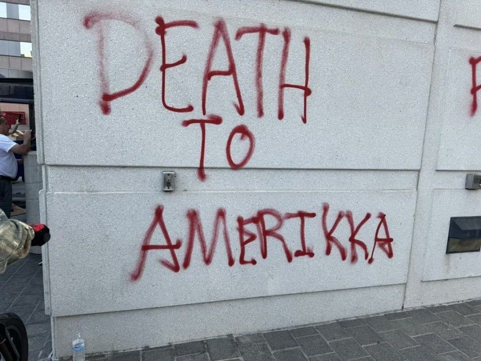 Graffiti reading "Death to Amerikka" sprayed in red on a wall.