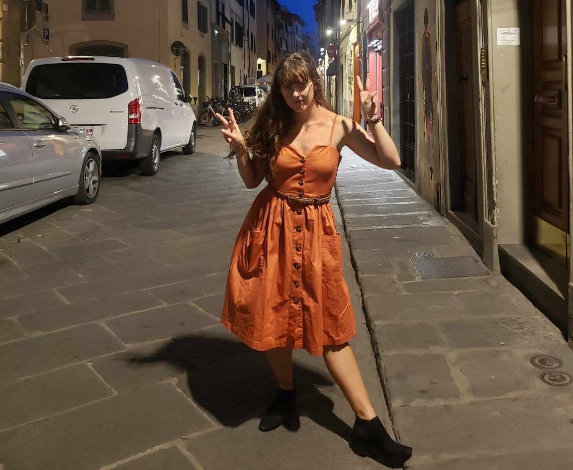 Emily holding up two peace signs on the streets of Florence at night.