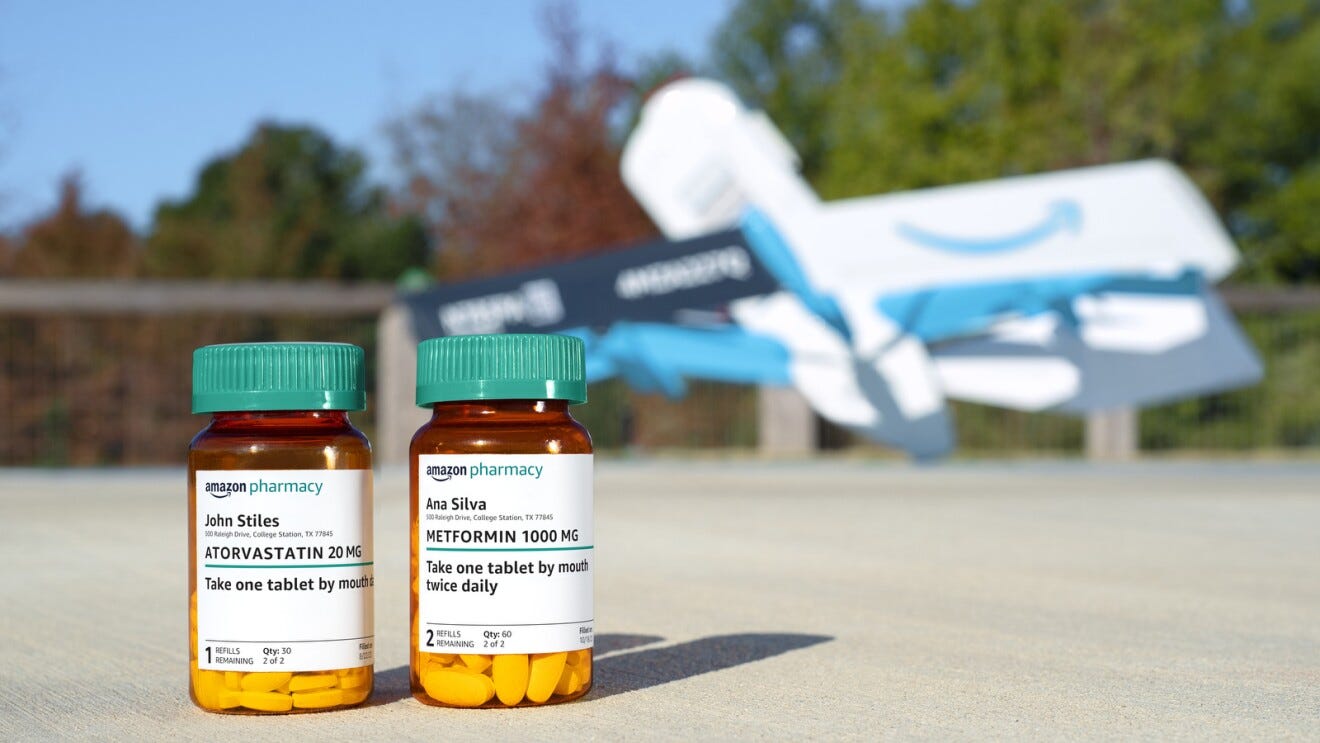 An image of two Amazon Pharmacy prescription bottles with an Amazon delivery drone blurred in the background. 