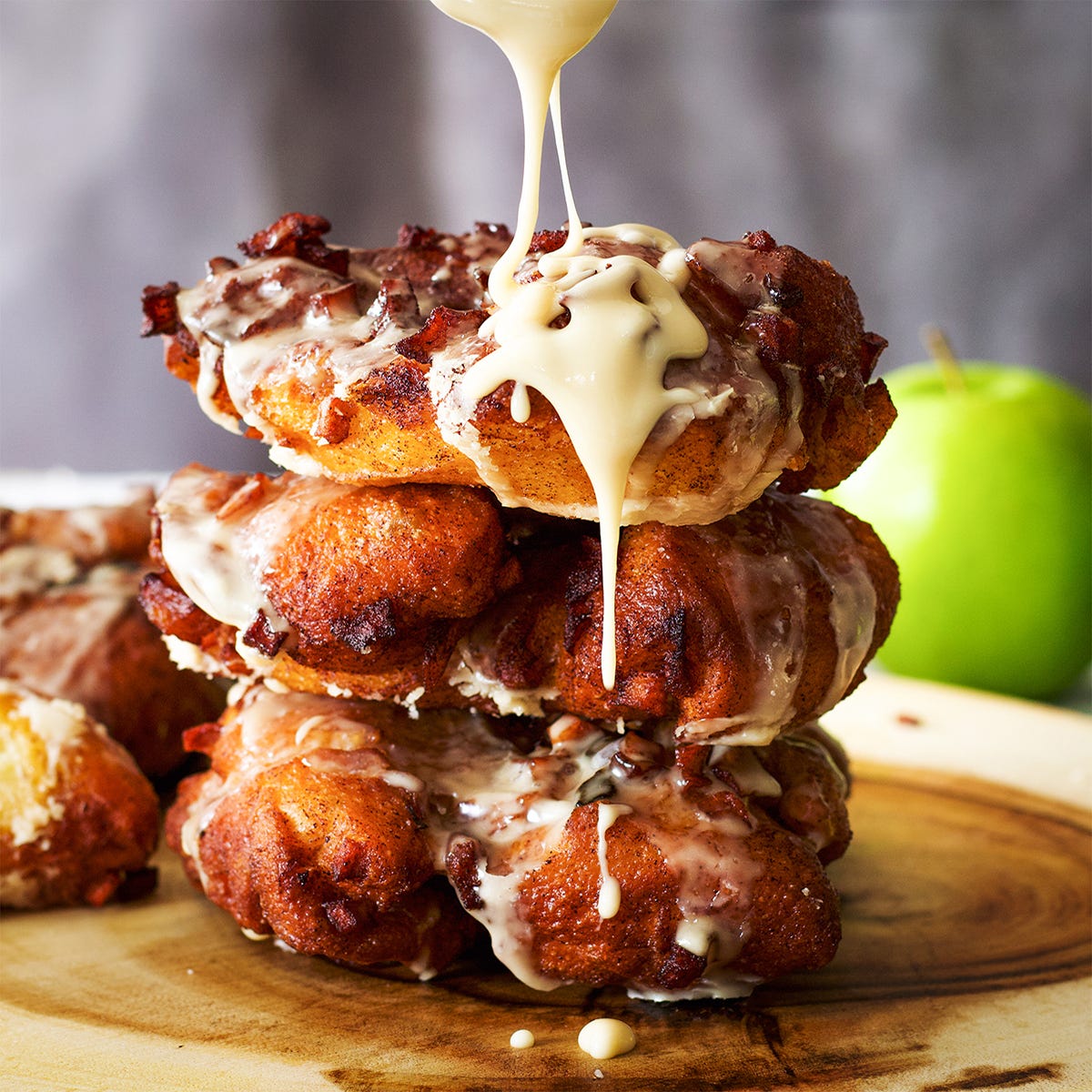 Maple icing dripping from a stack of apple fritters.