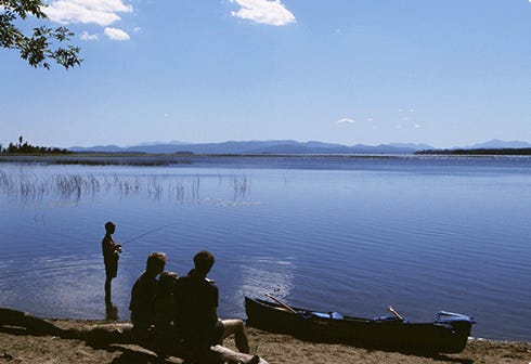 Family fishing on calm lake in Vermont.