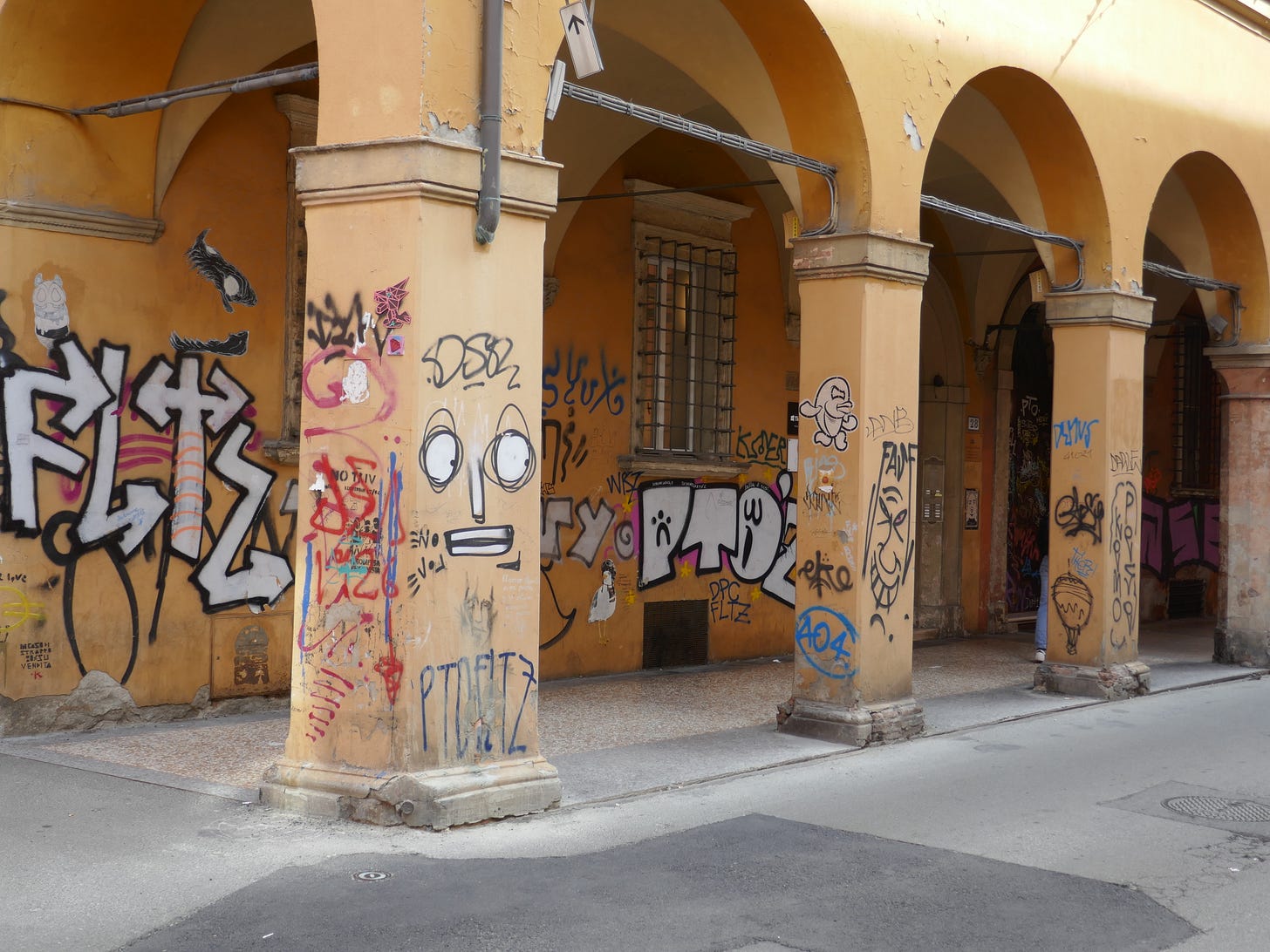 A portico covered entirely with street art including a large cartoon face.