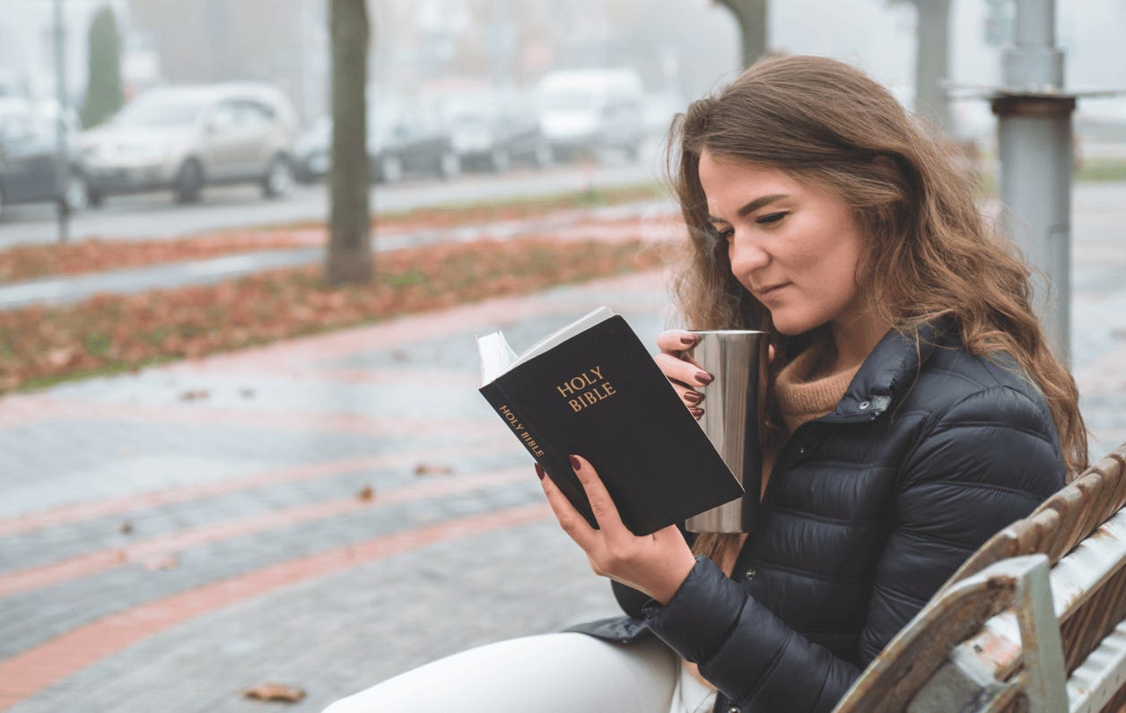 A person sitting on a bench reading a book

Description automatically generated