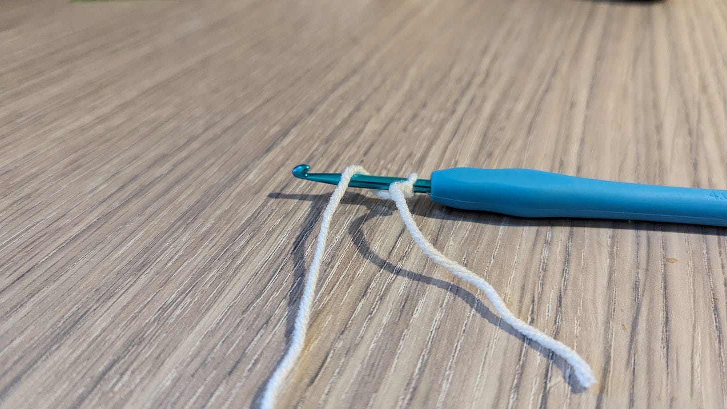 A crochet hook with a slip knot on the base, the working strand wrapped over the hook