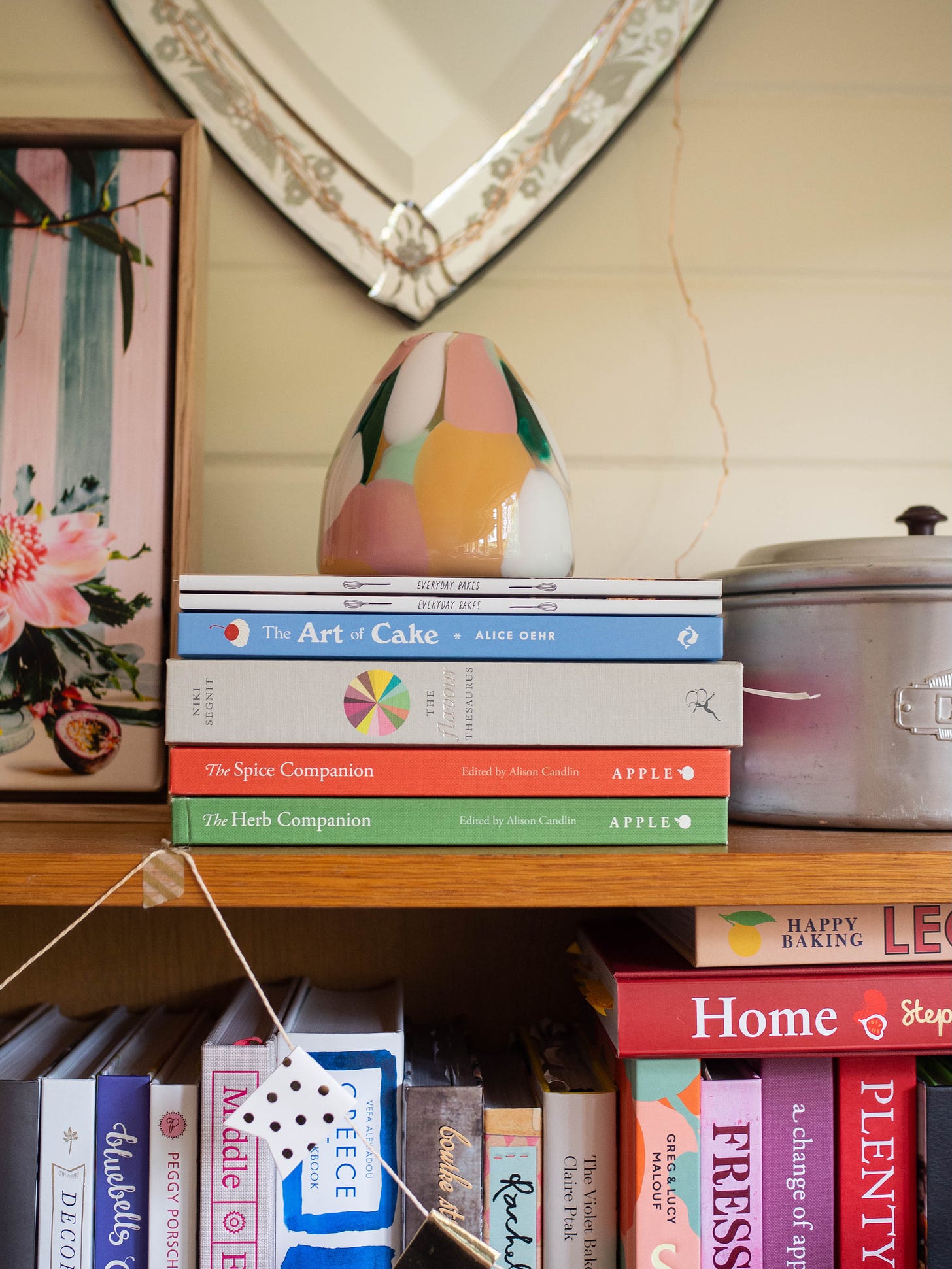 cookbooks on shelf with pink vase