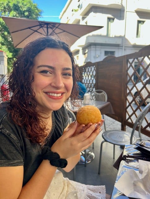 find best local food when you travel - posing happily with an Arancini from a local cafe in Catania, Sicily
