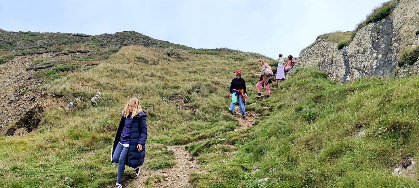 A rough and steep path leading down a hill, with five women walking down it