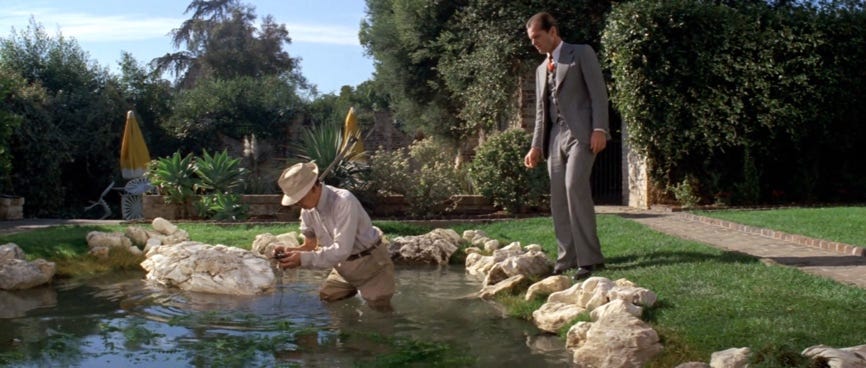 A person in a suit and hat standing in a pond

Description automatically generated