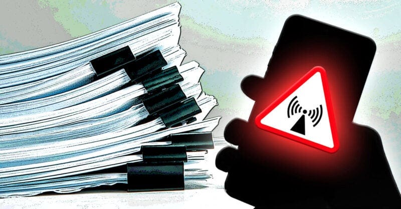 stack of documents with hand holding cellphone with radiation symbol on top