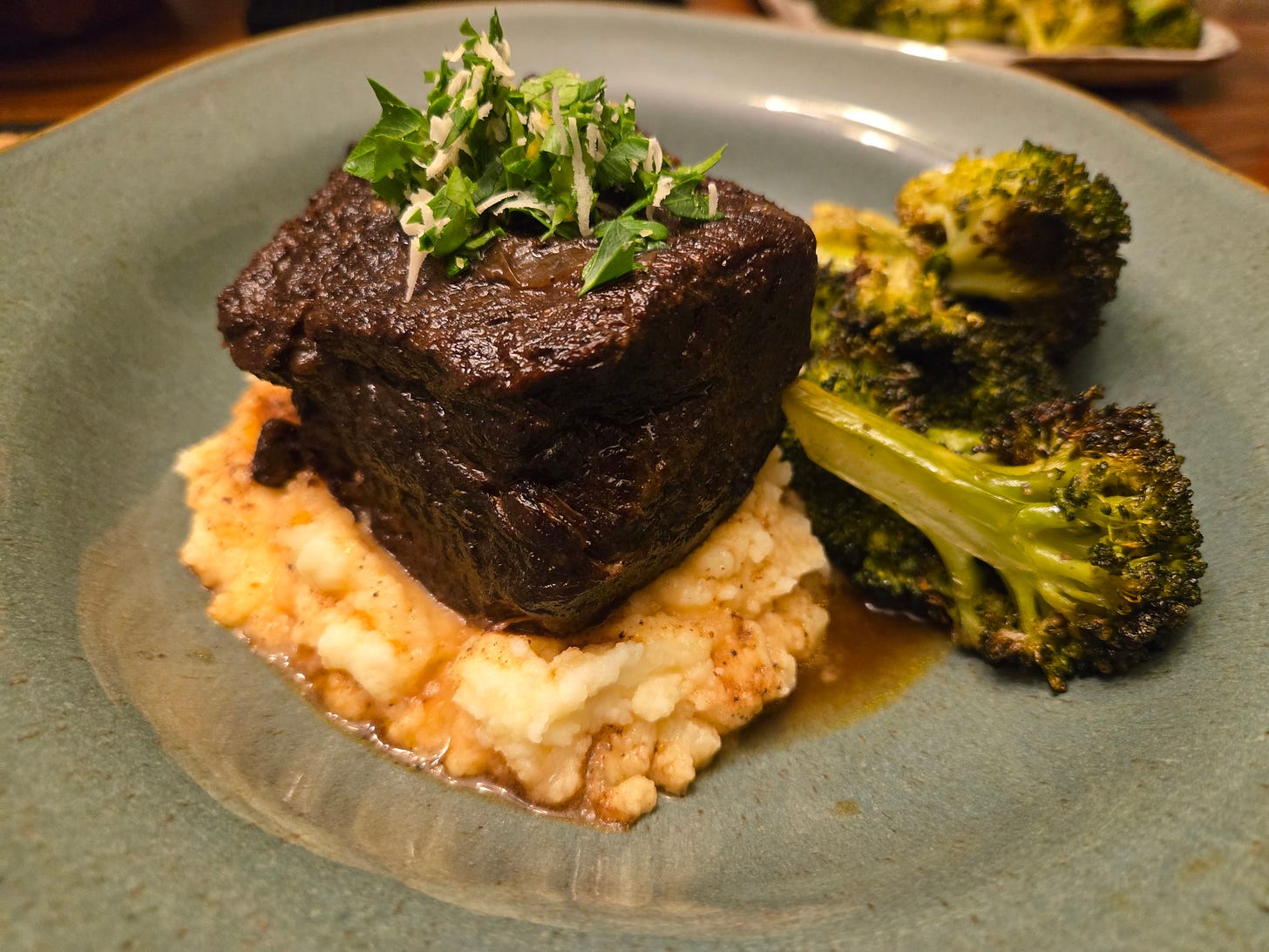 Braised short rib topped with horseradish gremolata on a bed of mashed potatoes with roasted broccoli on the side.