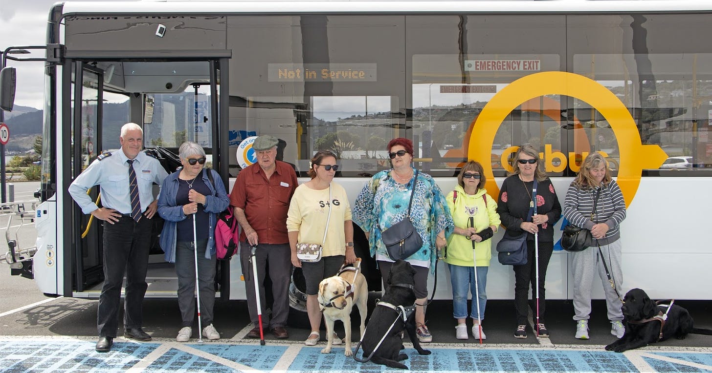 Blind Citizens Otago Network and their canine companions stand outside a new e-bus.