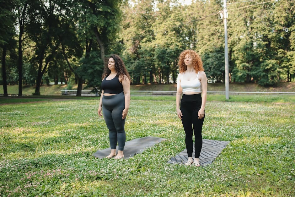 Two women in active wear performing yoga on mats in a scenic park setting, embodying wellness and mindfulness.