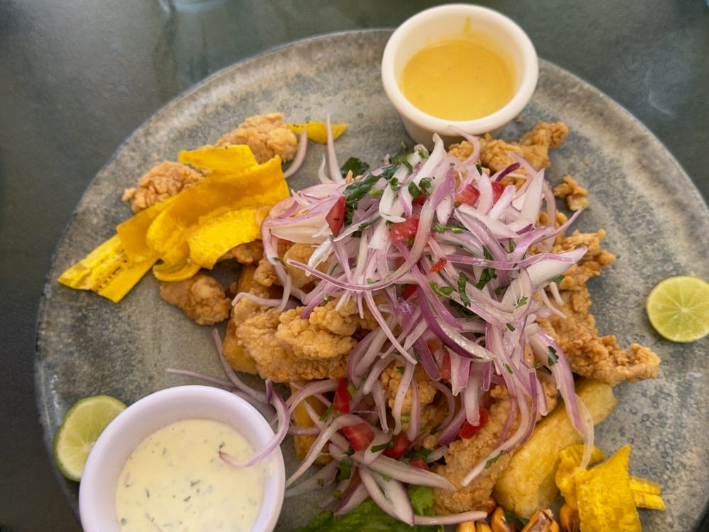 A large plate of Chicharrón de Pescado, fried fish with red onion salad