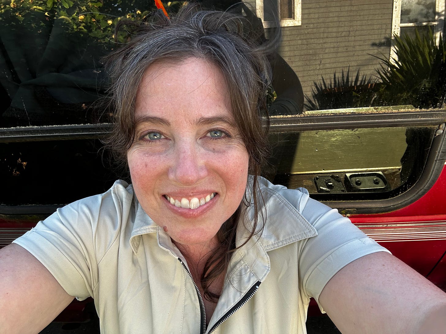 A selfie of a woman (the author) standing in front  of a red van (the original seat of the Rolling Desk).