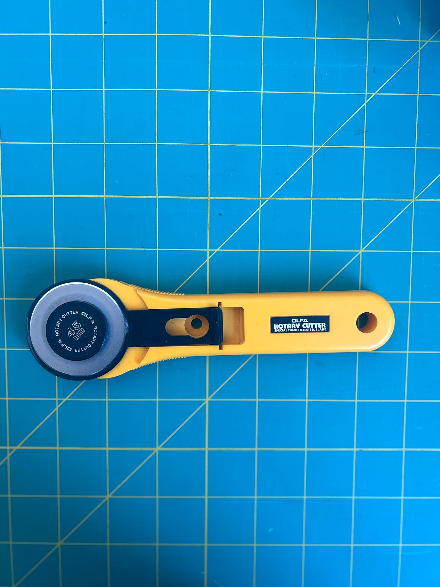 45 mm yellow Olfa rotary cutter on a green background