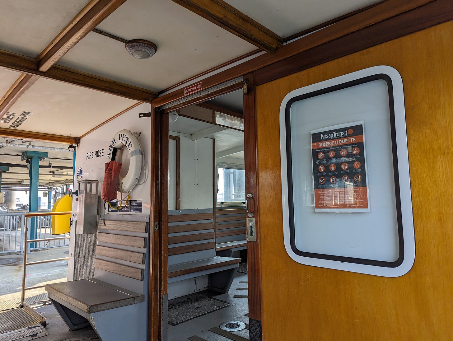 The interior of a cute old fashioned ferry, with wood paneling on the walls and brass fixtures. 
