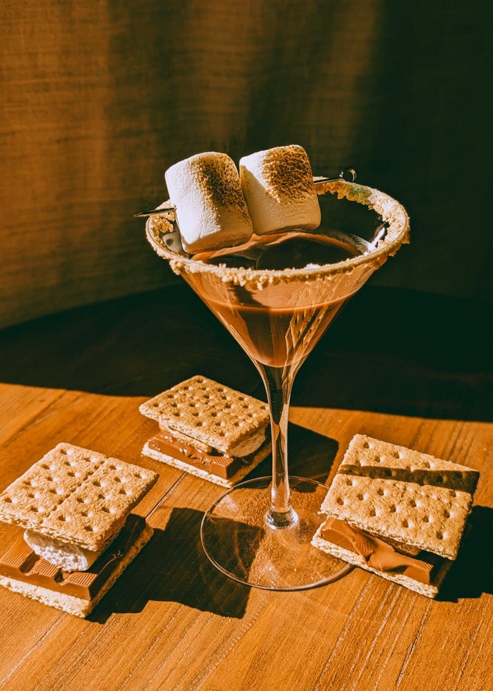chocolate martini with toasted marshmallows and s'mores surrounding it