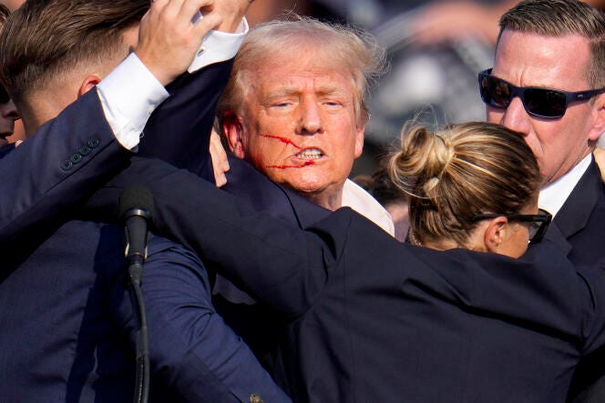 Republican presidential candidate former President Donald Trump is helped off the stage by US Secret Service agents at a campaign event in Butler, Pennsylvania, on Saturday, July 13, 2024.