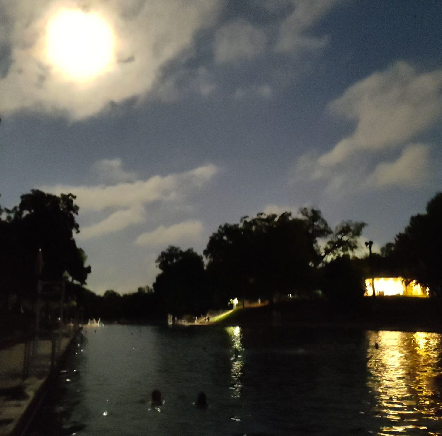 Barton Springs pool; shadows of trees around and a very bright moon in the upper left corner.