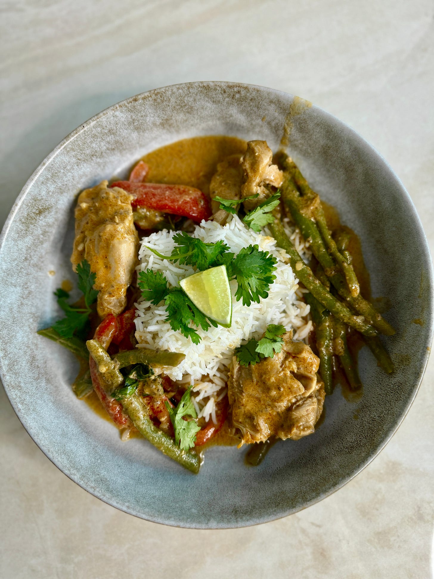 "Creamy red Thai coconut curry with chicken, red bell peppers, and string beans, simmered in a spiced coconut milk sauce and garnished with fresh herbs."