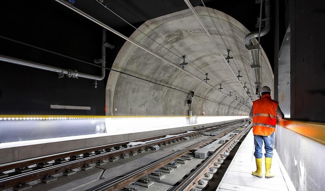 man standing beside train rail man standing beside train rail
