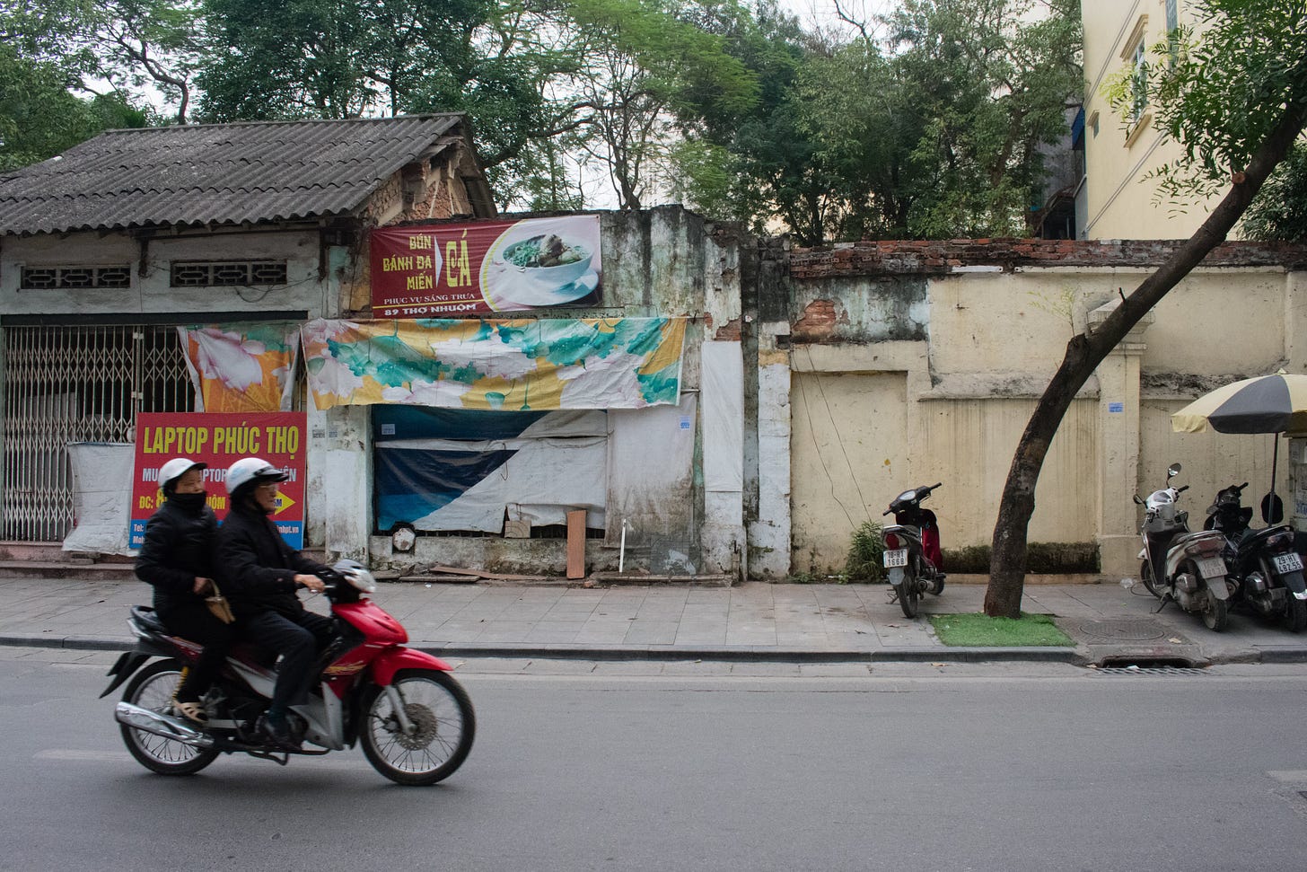 Two people on a scooter on a street in Hanoi