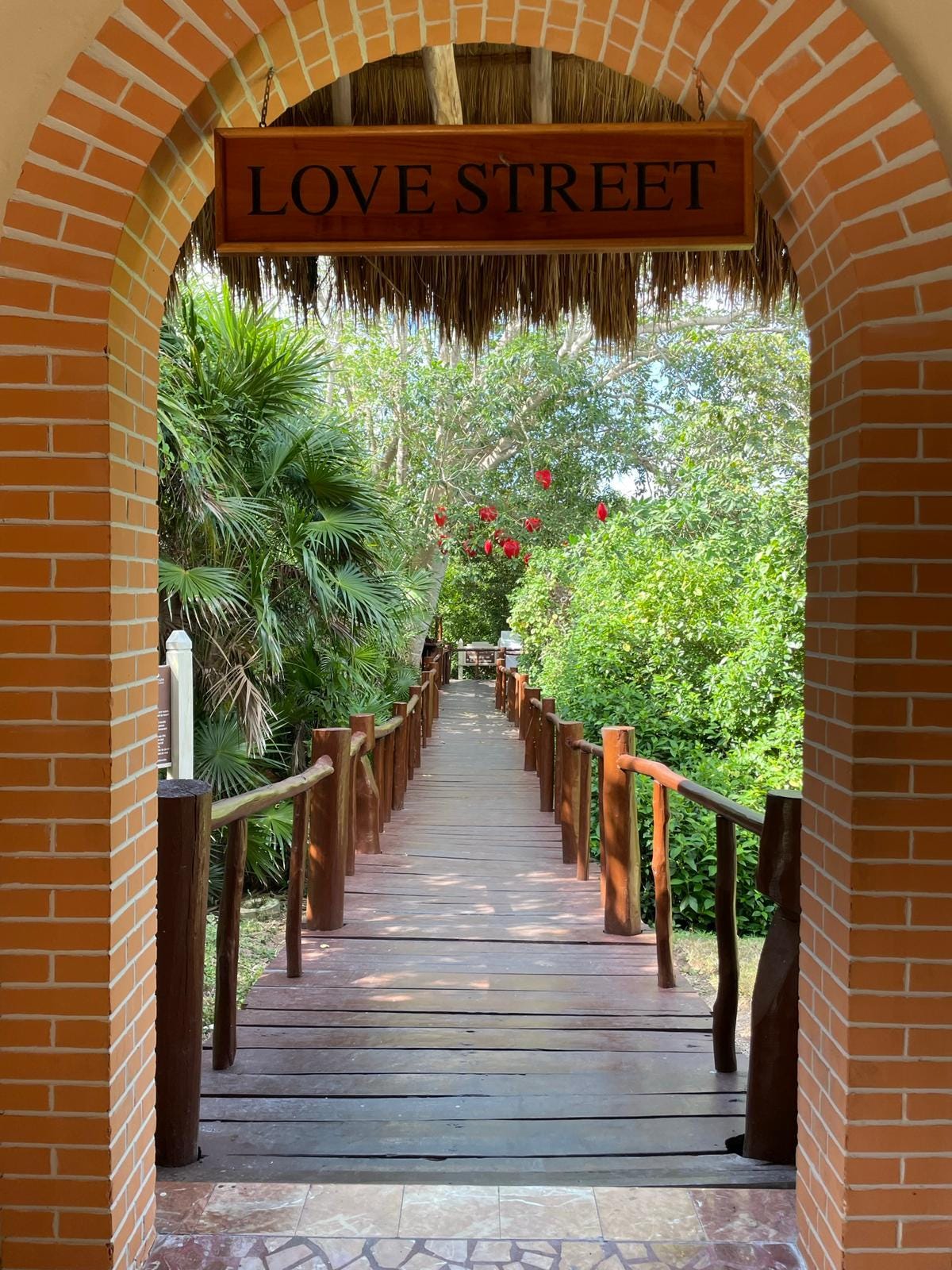 Archway into a lush garden with the sign above the door reading "Love Street".