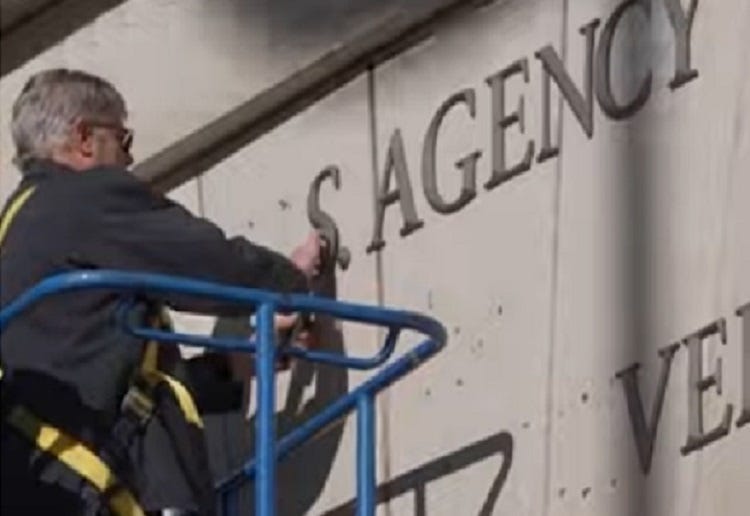 Video screenshot of a worker on a hydraulic lift pulling metal letters that spelled out 'U.S. AGENCY FOR INTERNATIONAL DEVELOPMENT,' one by one, from the facade of the agency's headquarters in Washington DC Video screenshot of a worker on a hydraulic lift pulling metal letters that spelled out 'U.S. AGENCY FOR INTERNATIONAL DEVELOPMENT,' one by one, from the facade of the agency's headquarters in Washington DC