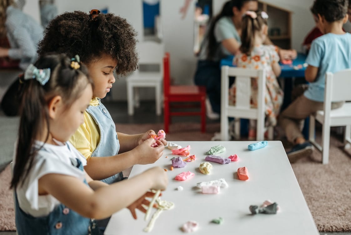 Free 2 Girls Sitting at the Table and Sculpt from Plasticine  Stock Photo