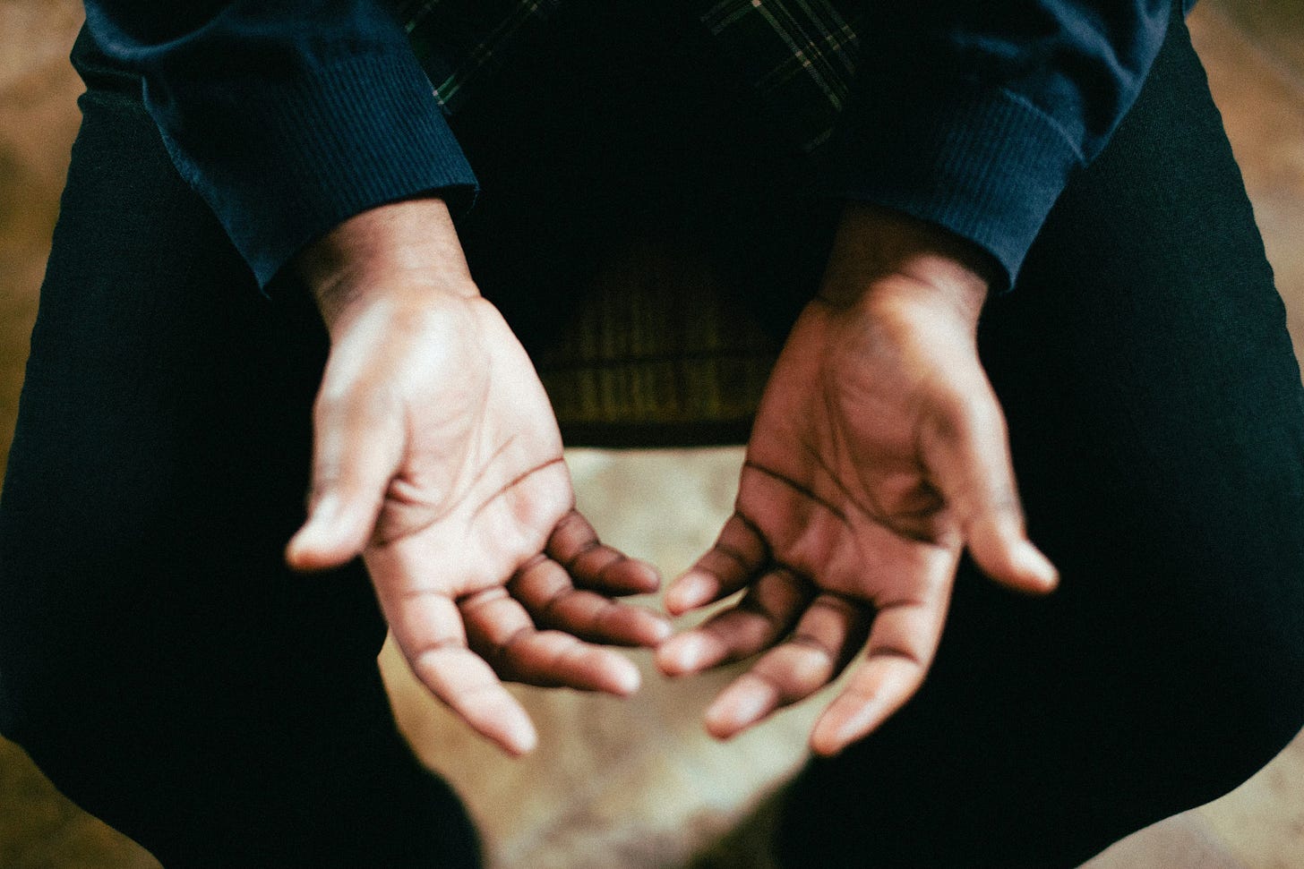 close up of a man's hands open on his lap in a posture of surrender