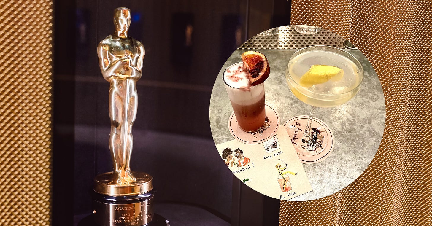 An Oscar / Academy award at the Academy museum alongside two fancy cocktails