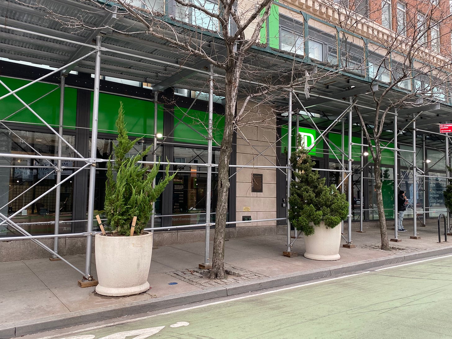 A high rise building with a TD Bank on the ground floor. There is construction scaffolding across the front a plaque just visible near the door.