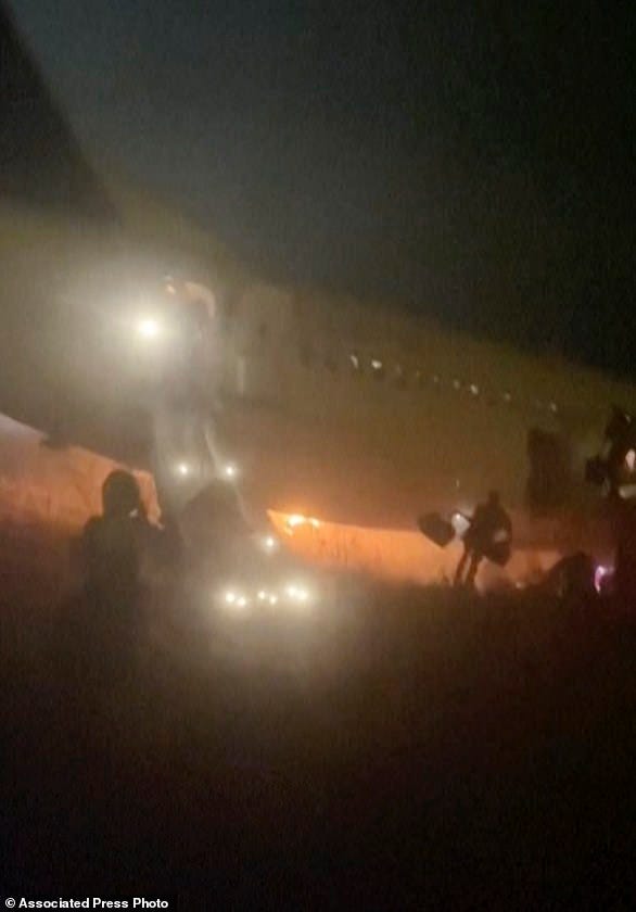 In this grab taken from video people jump down emergency slides, running from a plane, in Dakar, Senegal, Wednesday, May 8, 2024. A Boeing 737 plane carrying 85 people caught fire and skidded off a runway at the airport in Dakar, Senegal's capital, injuring 11 people