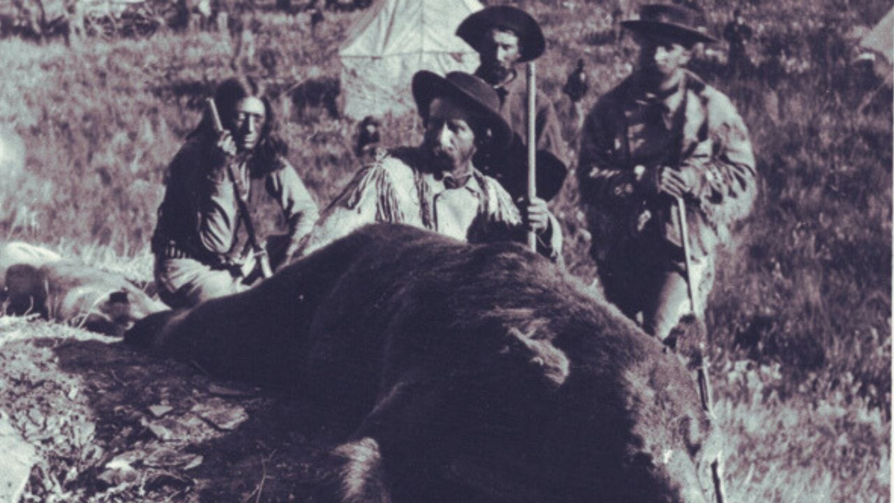 Photo of Sgt Noonan, George Custer, and others posing with a dead grizzly bear