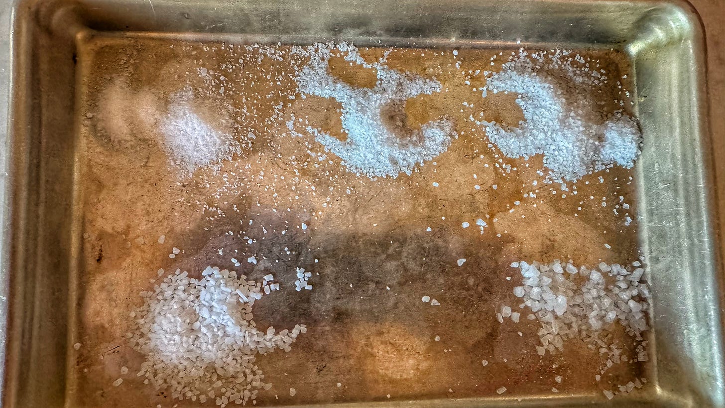 A quarter sheet pan with five piles of different salts on it