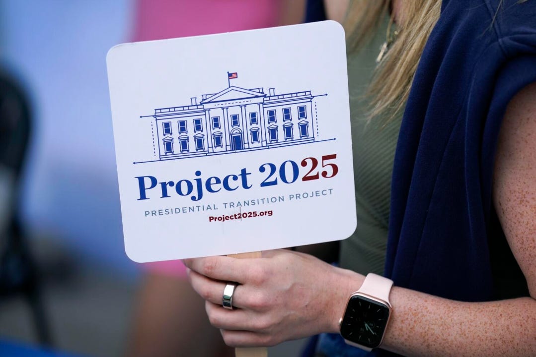 A supporter holds a Project 2025 fan in the group’s tent at the Iowa State Fair on Aug. 14, 2023. (Photo cred: Charlie Neibergall / Associated Press)