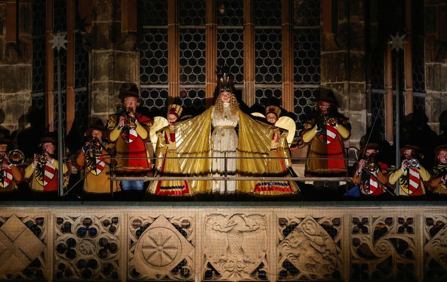 Costumed performers stand on a high outdoor balcony during a performance.