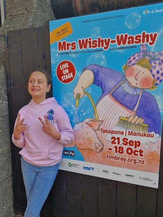 photo of 11yo in front of the poster for Mrs Wishy-Washy. she is smiling and giving peace fingers.