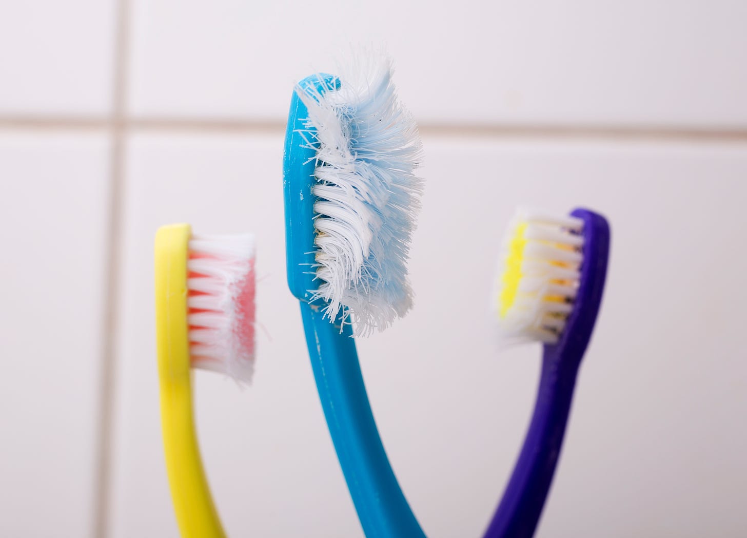 A frayed toothbrush surrounded by two children's toothbrushes.